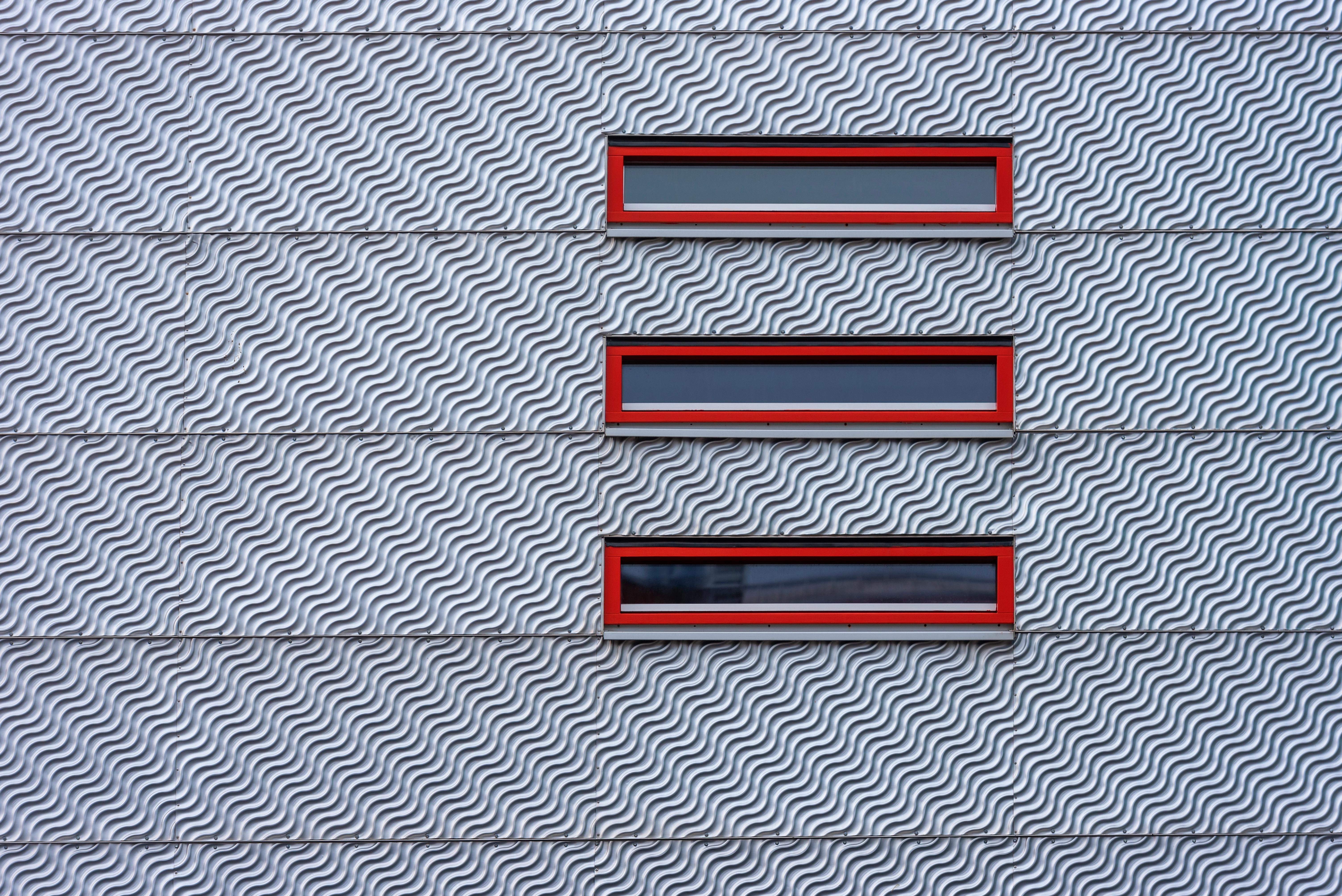 Kostenlos Architektonisches Detail einer modernen Fassade mit rot gerahmten Fenstern. Stock-Foto
