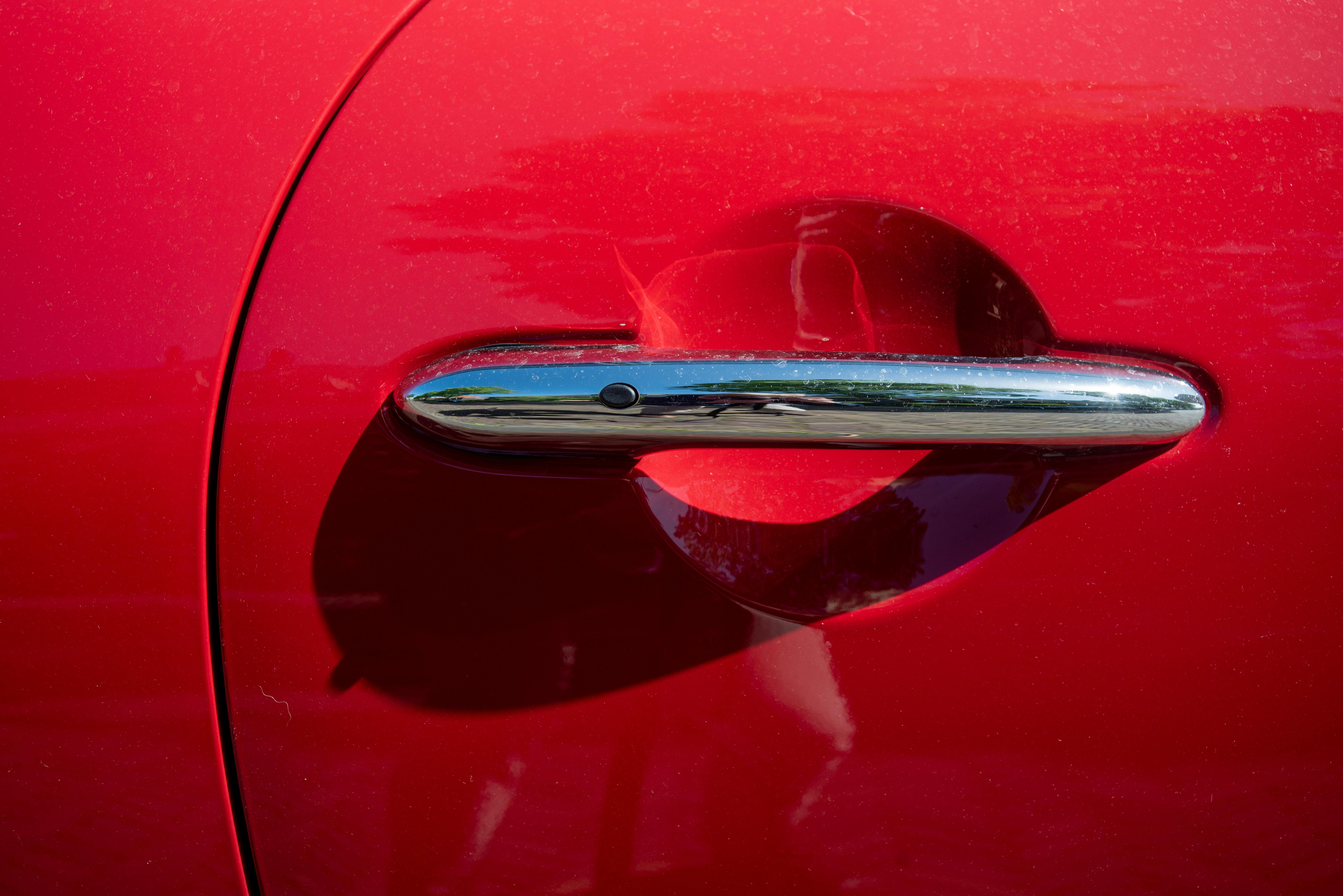 Detailed shot of a shiny chrome car door handle on a red vehicle.