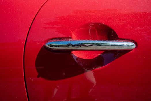 Detailed shot of a shiny chrome car door handle on a red vehicle.