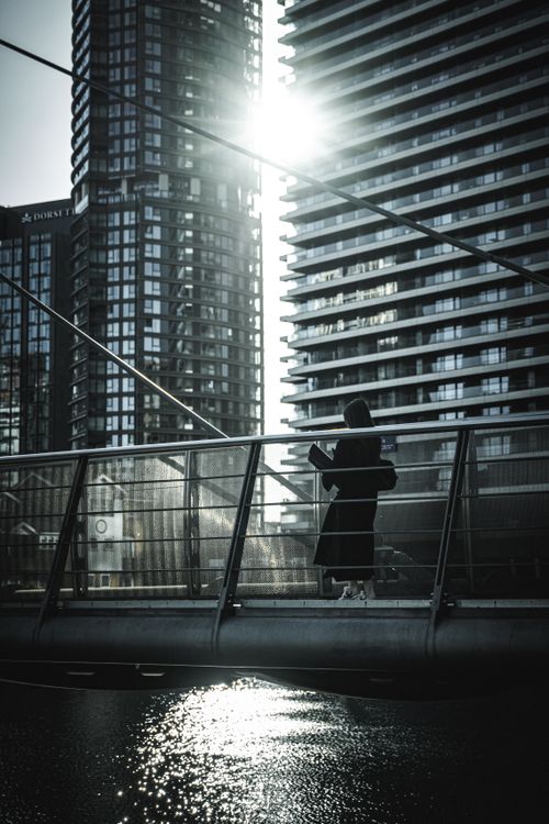 Free Silhouette of a woman walking on a bridge in London's modern architectural district. Stock Photo