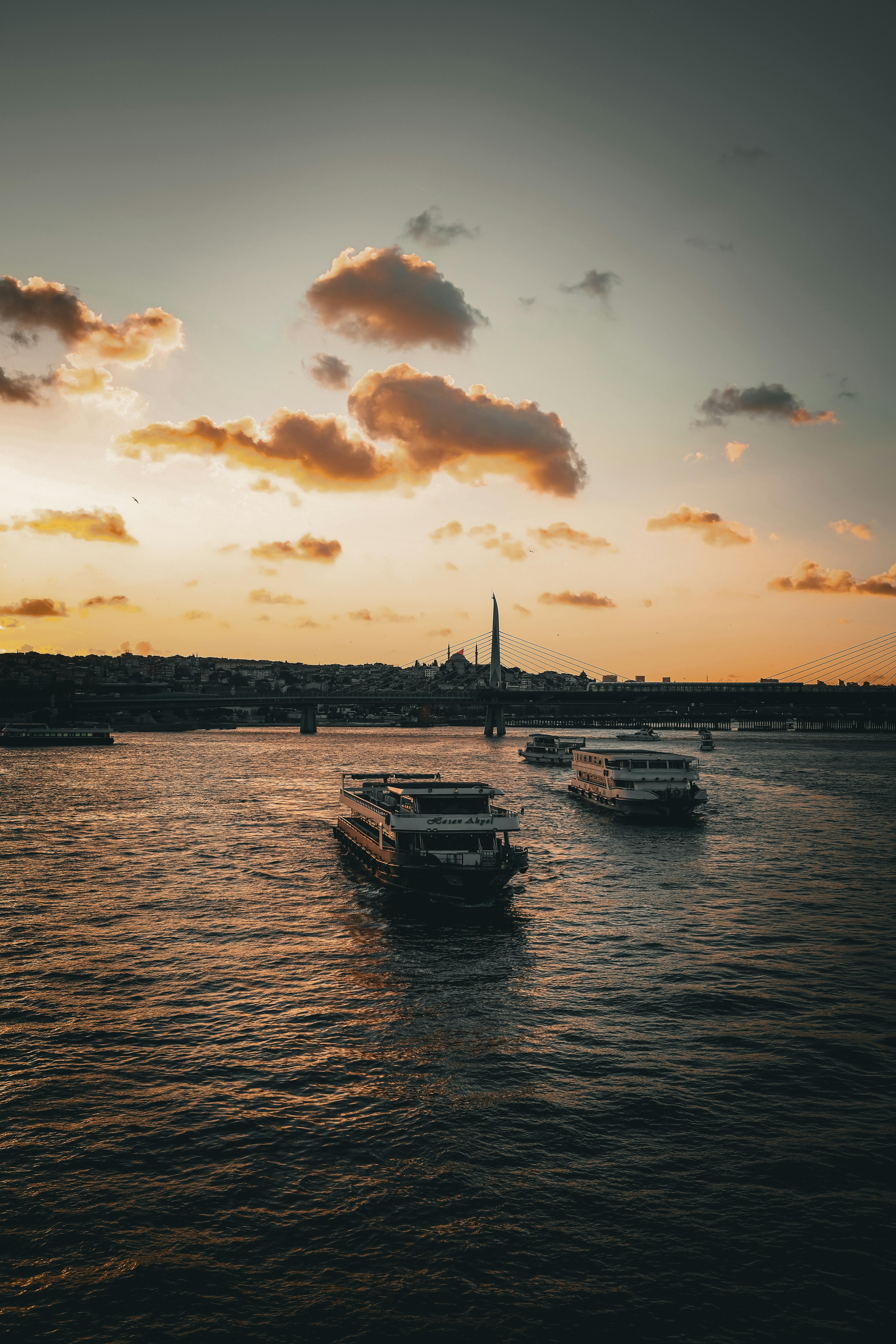 日落时，伊斯坦布尔的剪影映照在水面上，宁静的天际线景观中，水上船只静静地漂浮