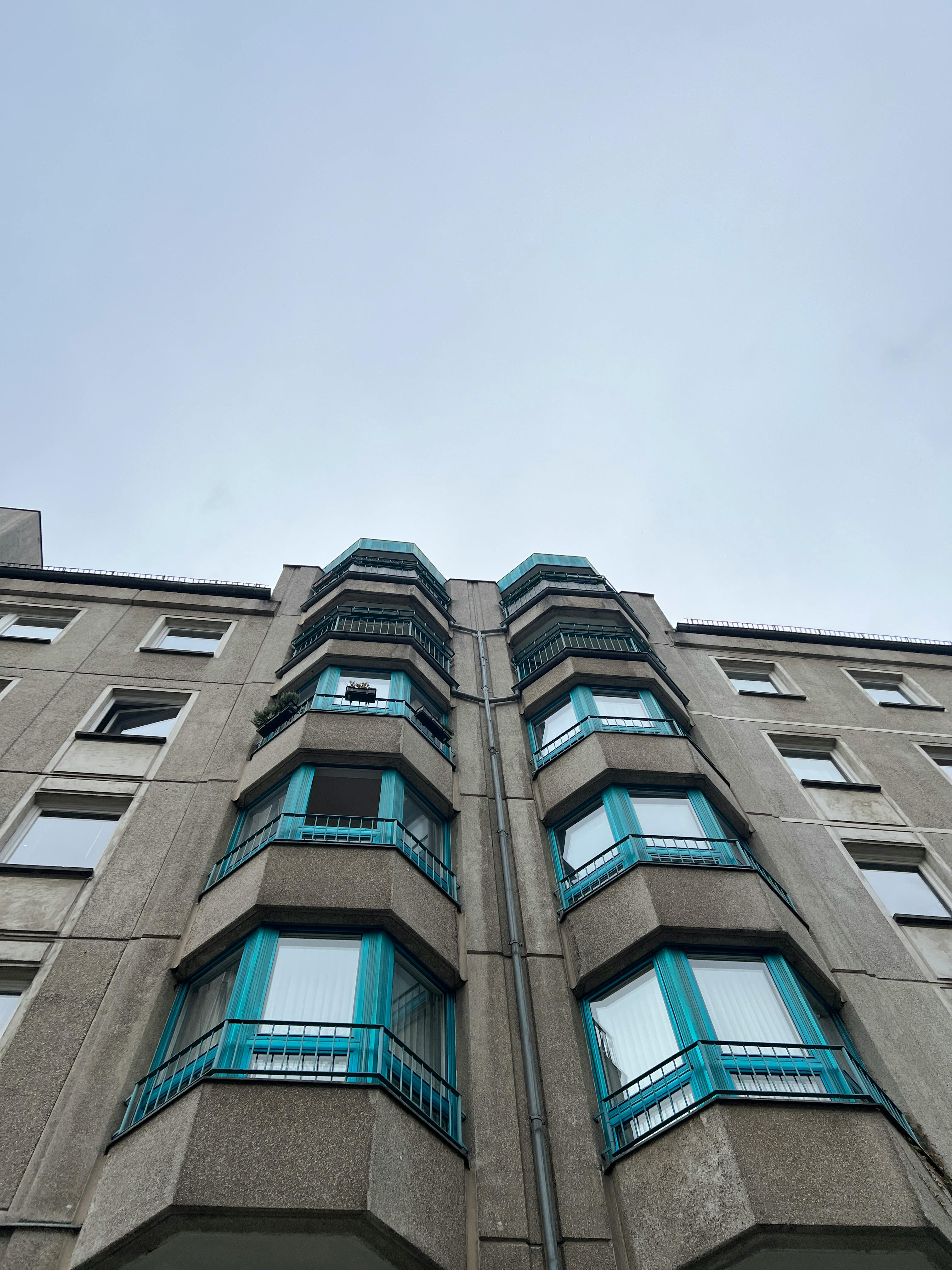 晴朗的天空映衬着蓝色窗户的高层公寓楼，展示出现代建筑的风格