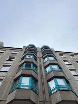 晴朗的天空映衬着蓝色窗户的高层公寓楼，展示出现代建筑的风格