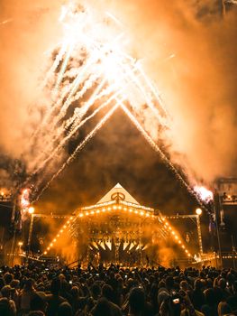 Vivid fireworks illuminate the night sky at the Glastonbury Festival, creating a breathtaking view over the vibrant crowd.