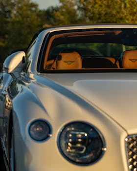 Elegant white sports car with brown leather interior captured at sunset, showcasing sleek design and luxury lifestyle.