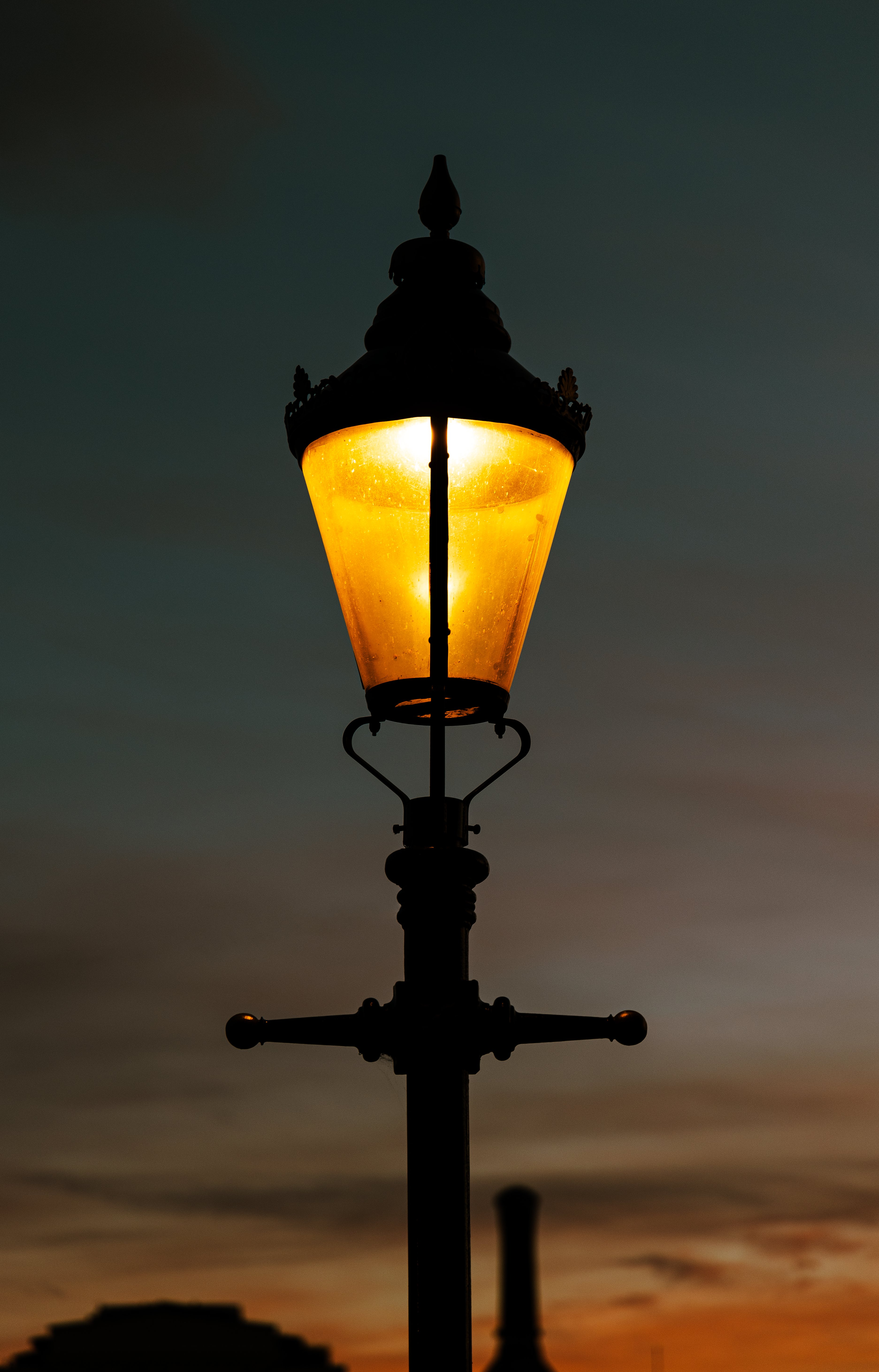 Ornate street lamp glowing gold against a dusk sky — photo by Anatolii Grytsenko on Pexels