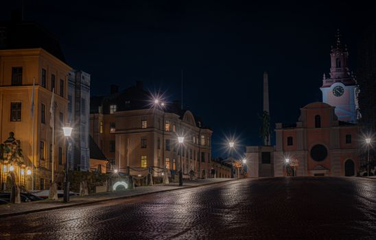 Streetlights illuminate a historic Stockholm scene with Gothic architecture at night.