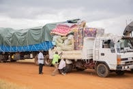 Men Loading Cargo onto Truck at Rural Station