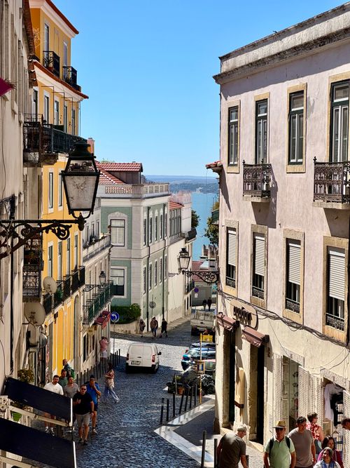 Free Pedestrian-friendly cobblestone street in Lisbon with colorful buildings on a sunny day. Stock Photo