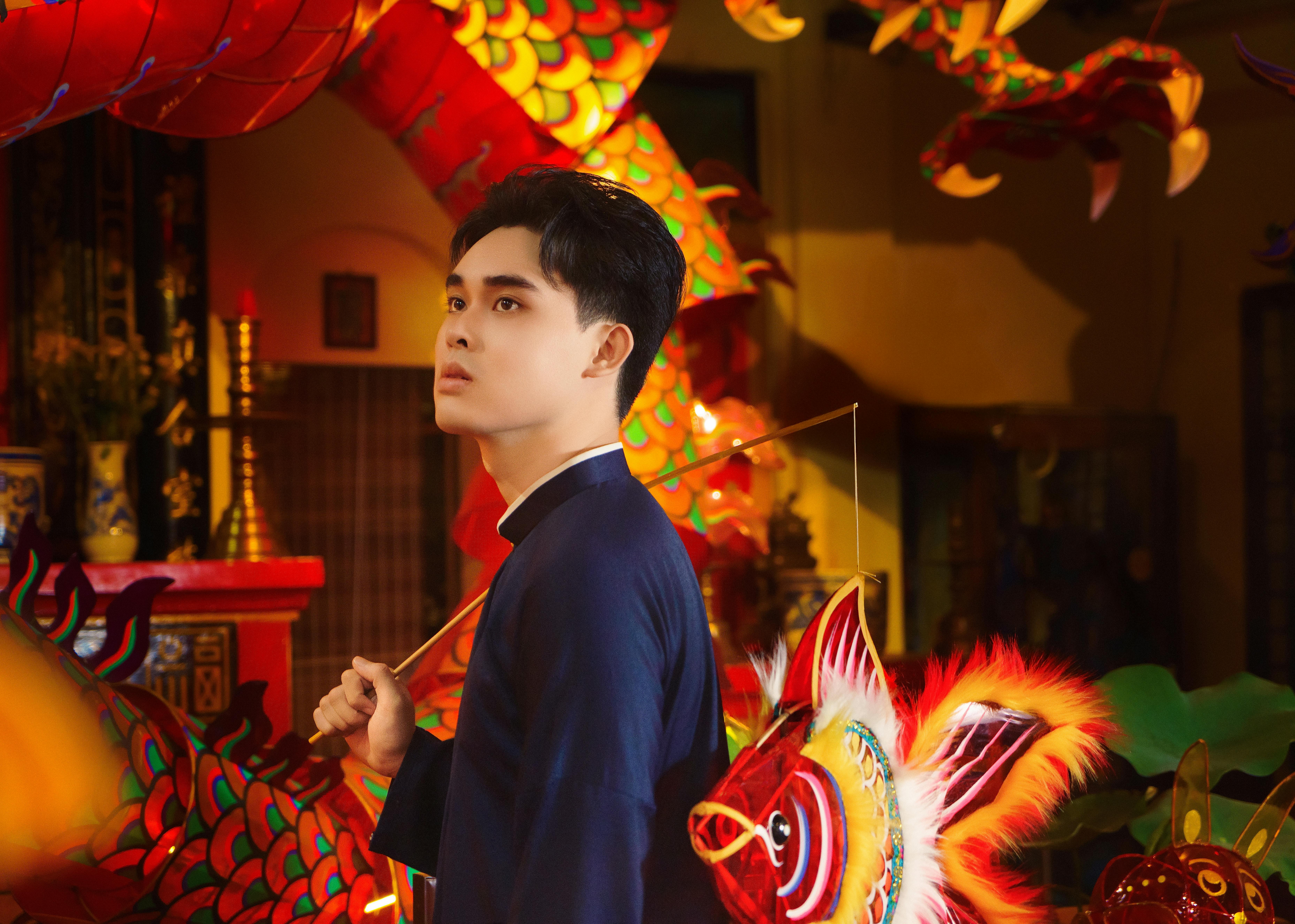Vietnamese man in traditional costume with vibrant dragon and fish lanterns.