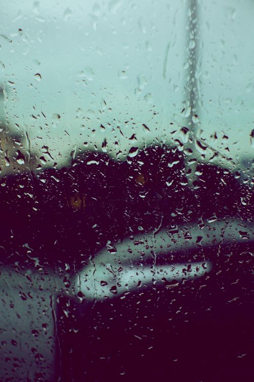 Free Closeup of raindrops on glass with blurred city background, creating a moody urban scene. Stock Photo