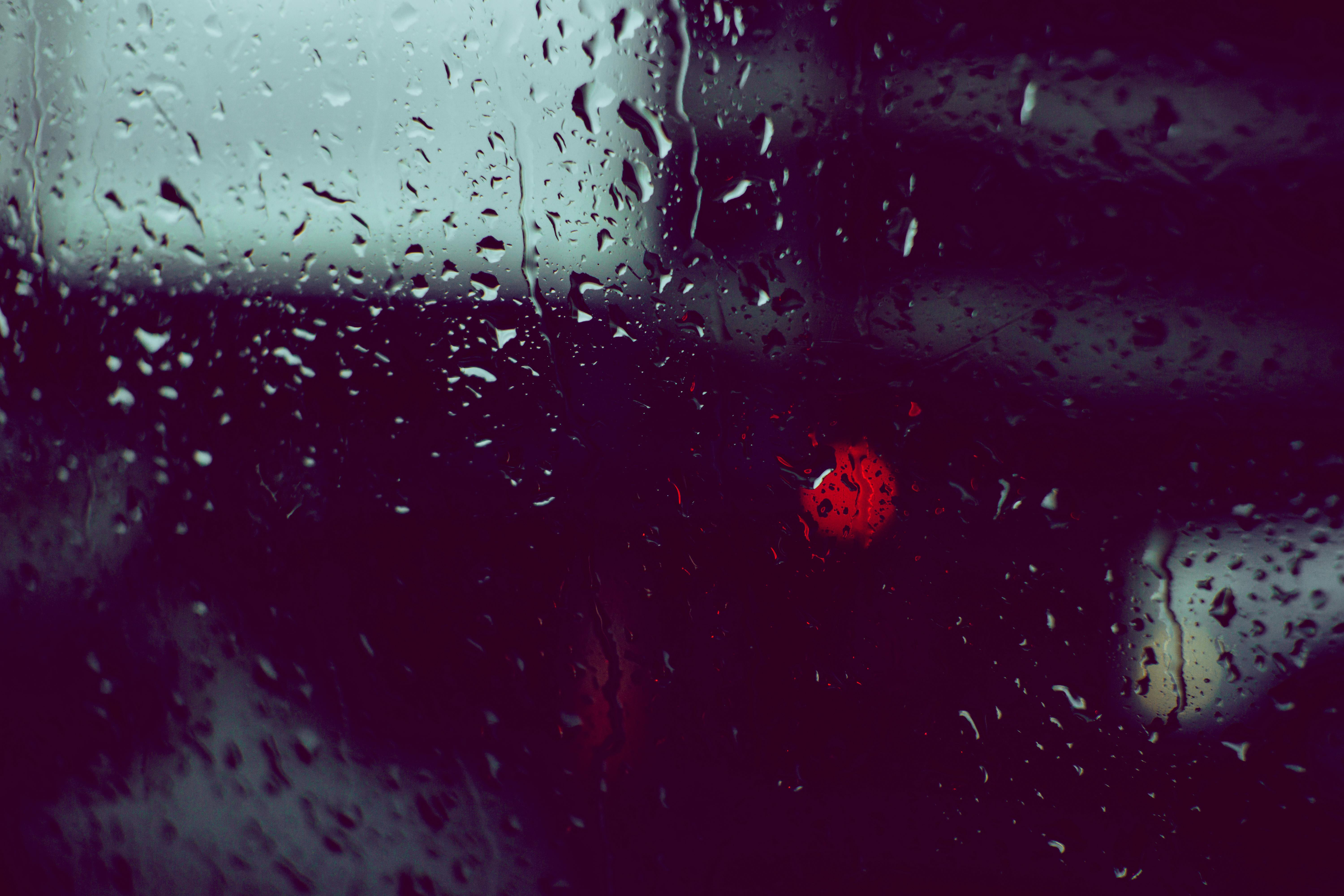 Δωρεάν Σταγόνες βροχής σε ένα παράθυρο με θολά φώτα της πόλης στο φόντο δημιουργούν μια μελαγχολική ατμόσφαιρα. Φωτογραφία από στοκ φωτογραφιών