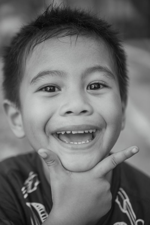 Free Black and white portrait of a happy child smiling with playful gestures, candid expression. Stock Photo