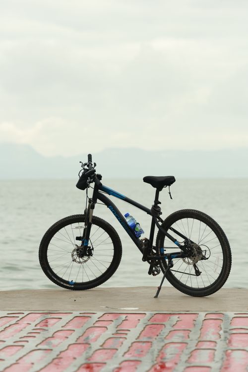 Free A mountain bike stands on a waterfront promenade with a peaceful ocean in the background. Stock Photo