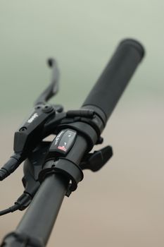 Detailed view of a bicycle handlebar featuring a brake lever and gear shifter outdoors.