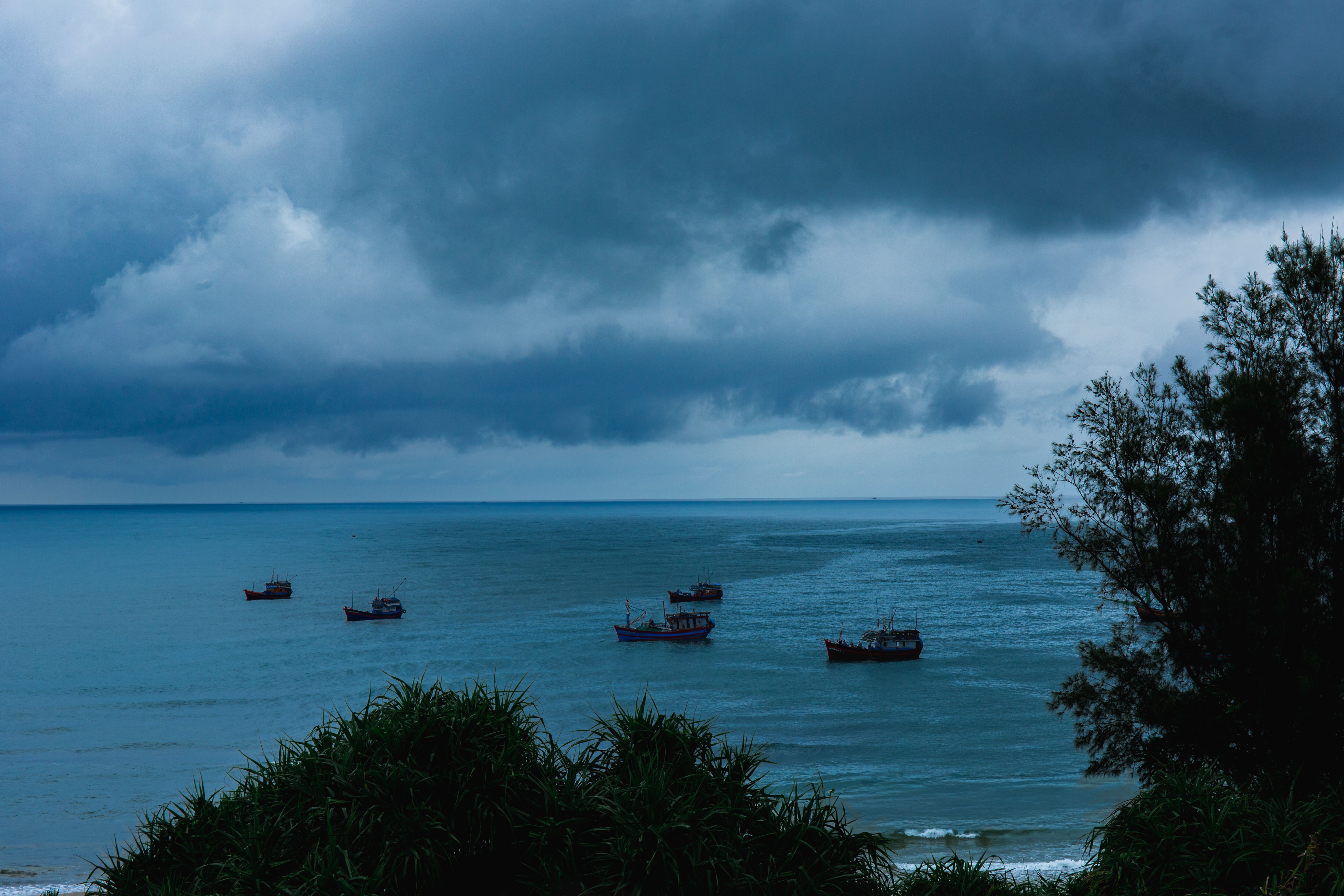 Stormy Sea with Fishing Boats Under Dramatic Sky · Free Stock Photo