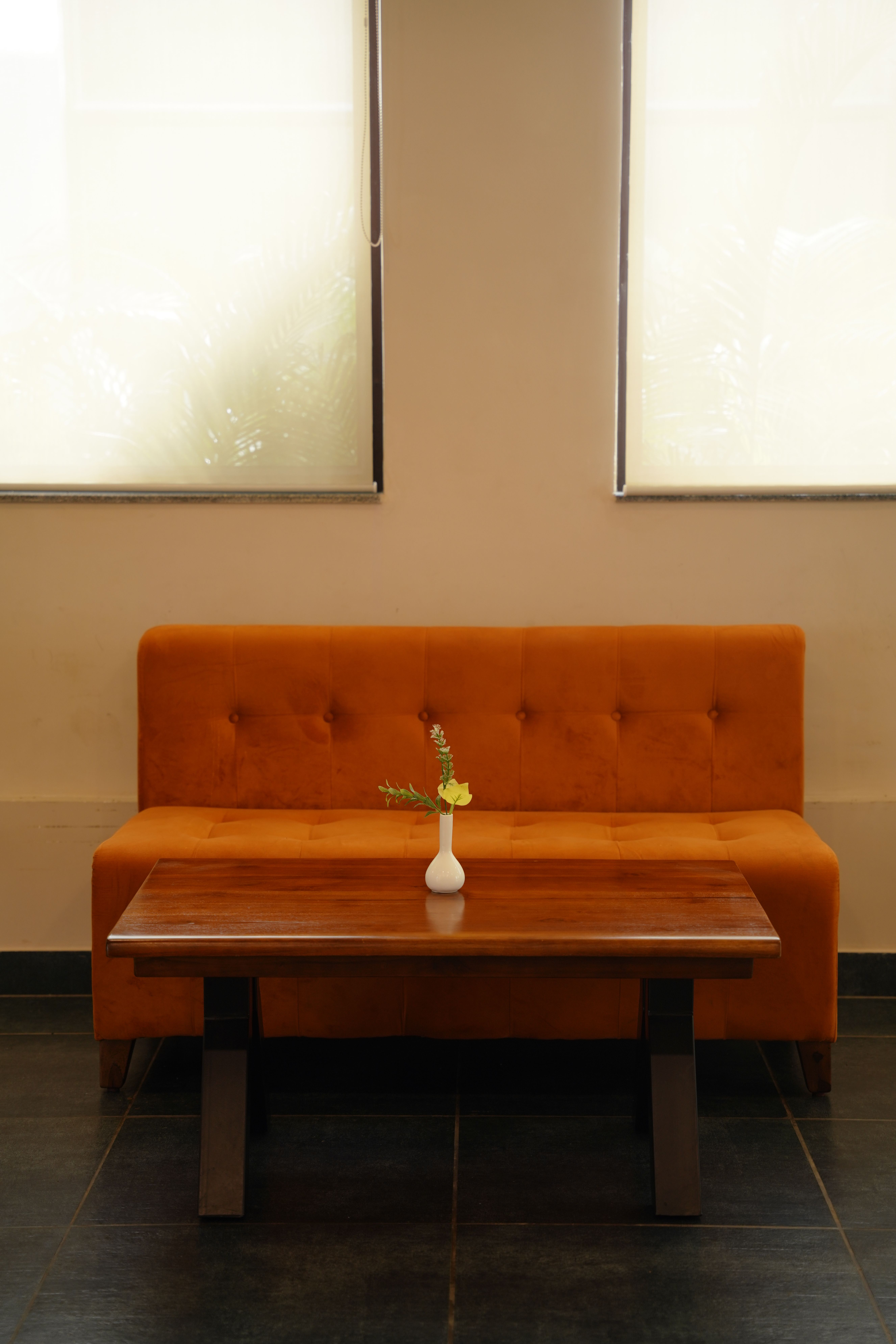 Modern living space features an orange sofa, wooden table, and vase, capturing minimalist interior design.