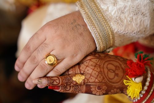 Free Close-up of henna adorned bride and groom hands with rings at an Indian wedding. Stock Photo
