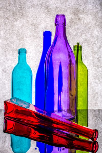 Coloured glass bottles on a reflective surface — photo by Valentin Ivantsov on Pexels