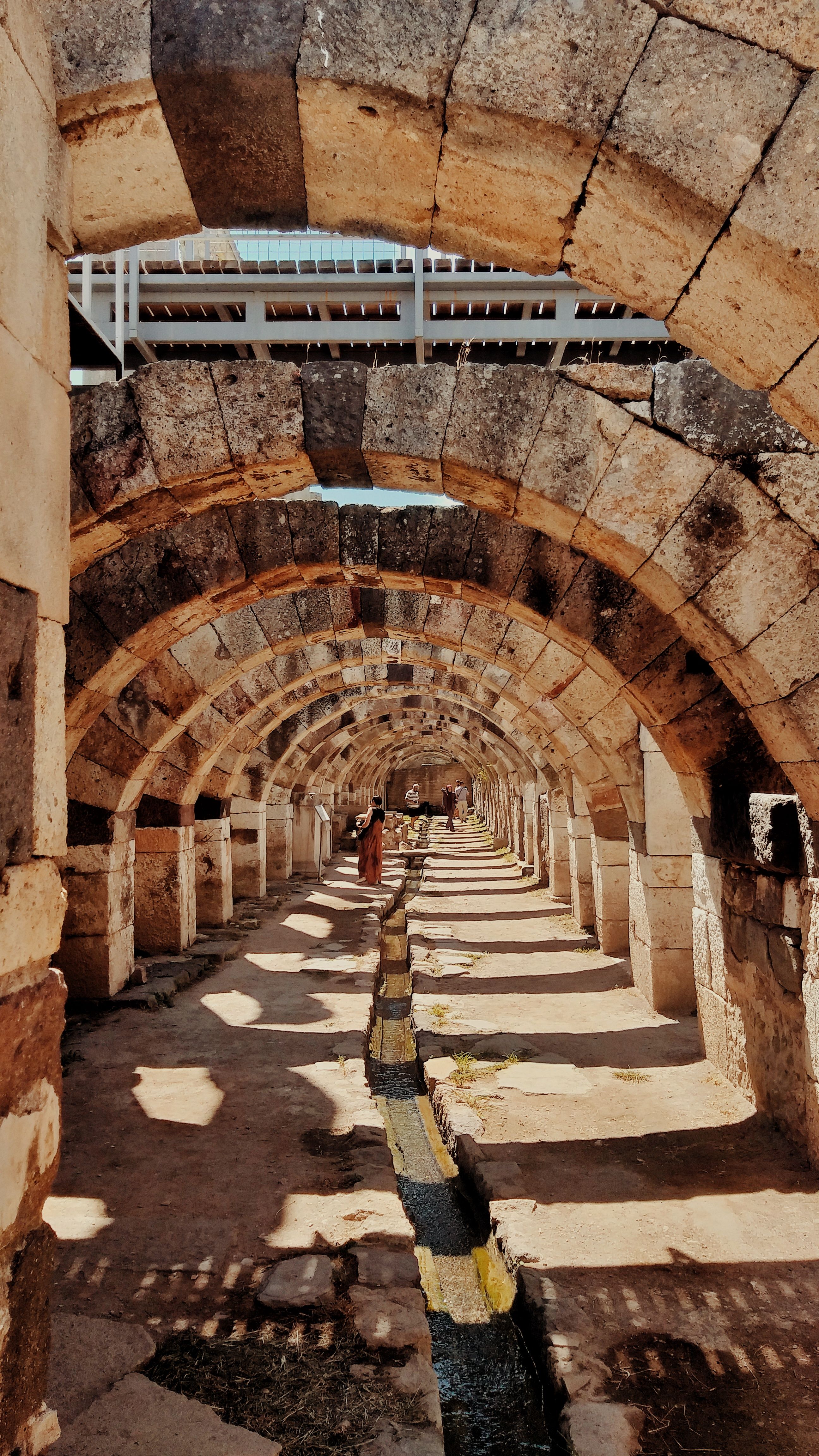 Ancient stone arches in İzmir, Türkiye, showcasing historical architecture and sunlight.