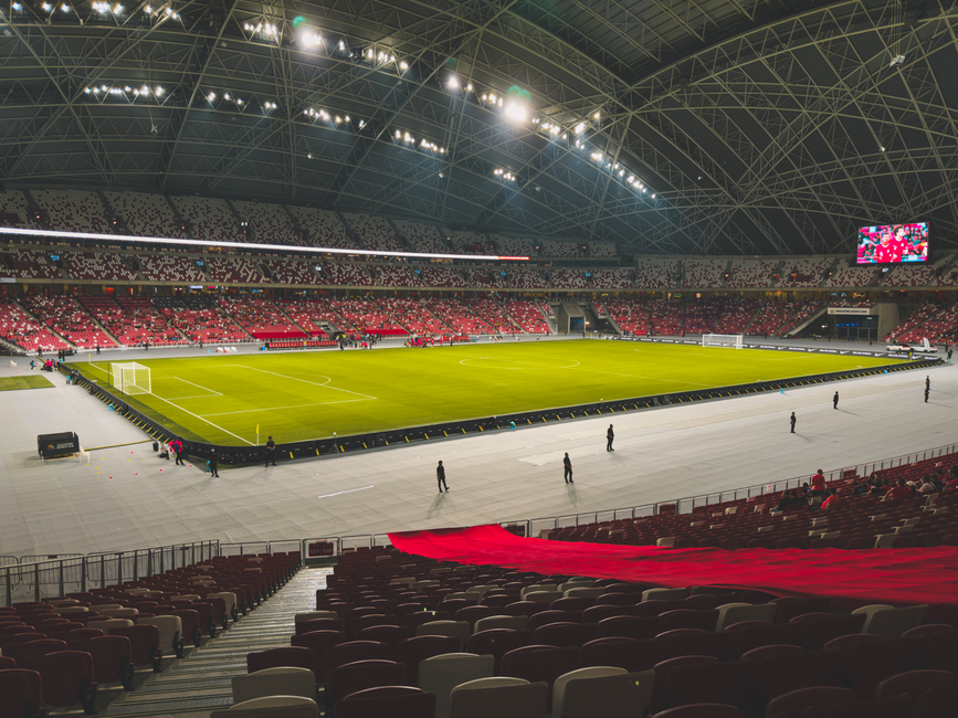 Spacious indoor soccer stadium with green field and illuminated seating area.