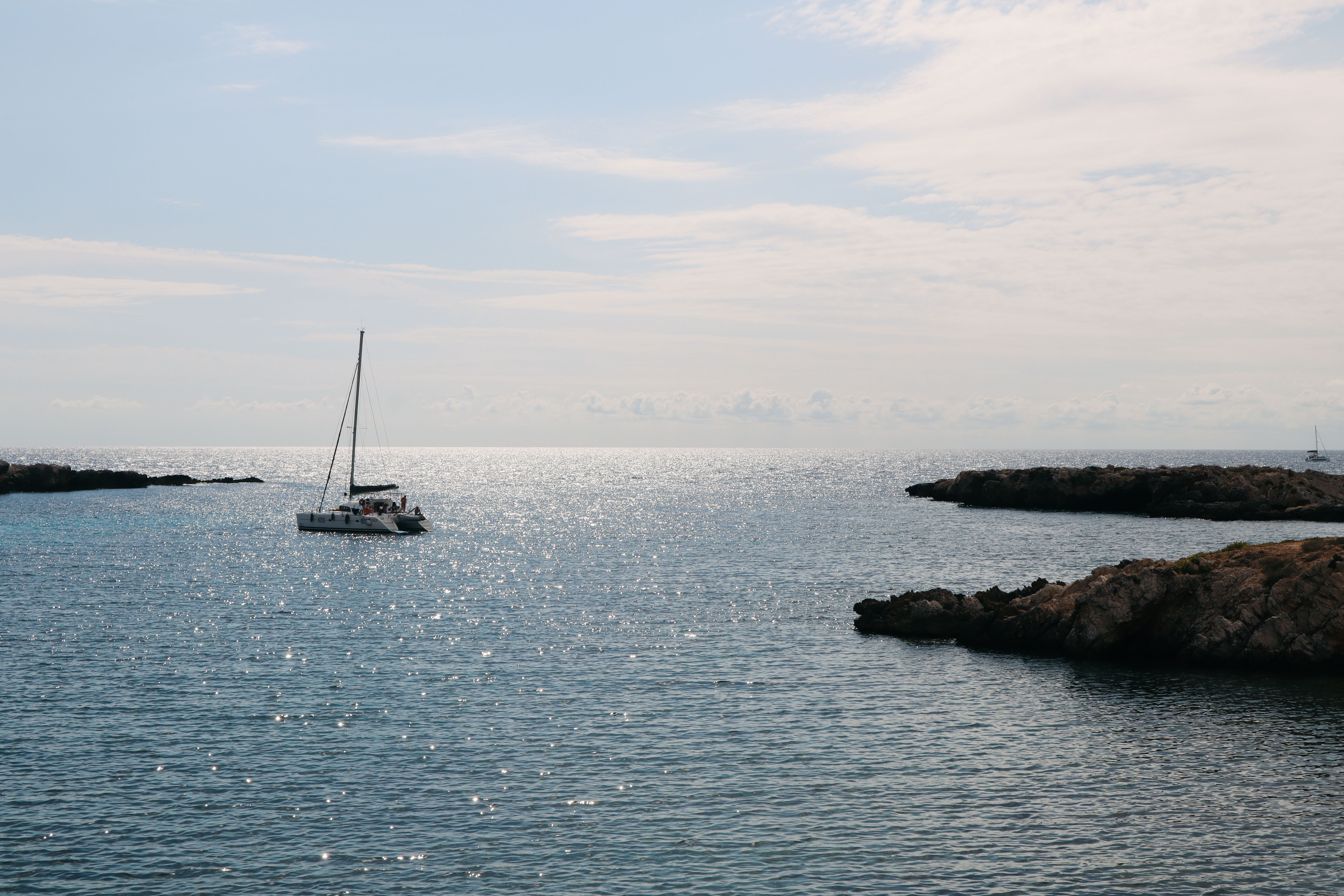 Best Tour to Figarolo Island with the Possibility to Observe Dolphins Review: A Complete Guide to This Unforgettable Sardinian Adventure Review 2026 - A serene sailboat on the sparkling waters off Sicilia's rocky coastline, capturing tranquility and adventure.