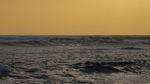 Free A breathtaking view of ocean waves under a golden sunset sky, creating a serene and dramatic seascape. Stock Photo