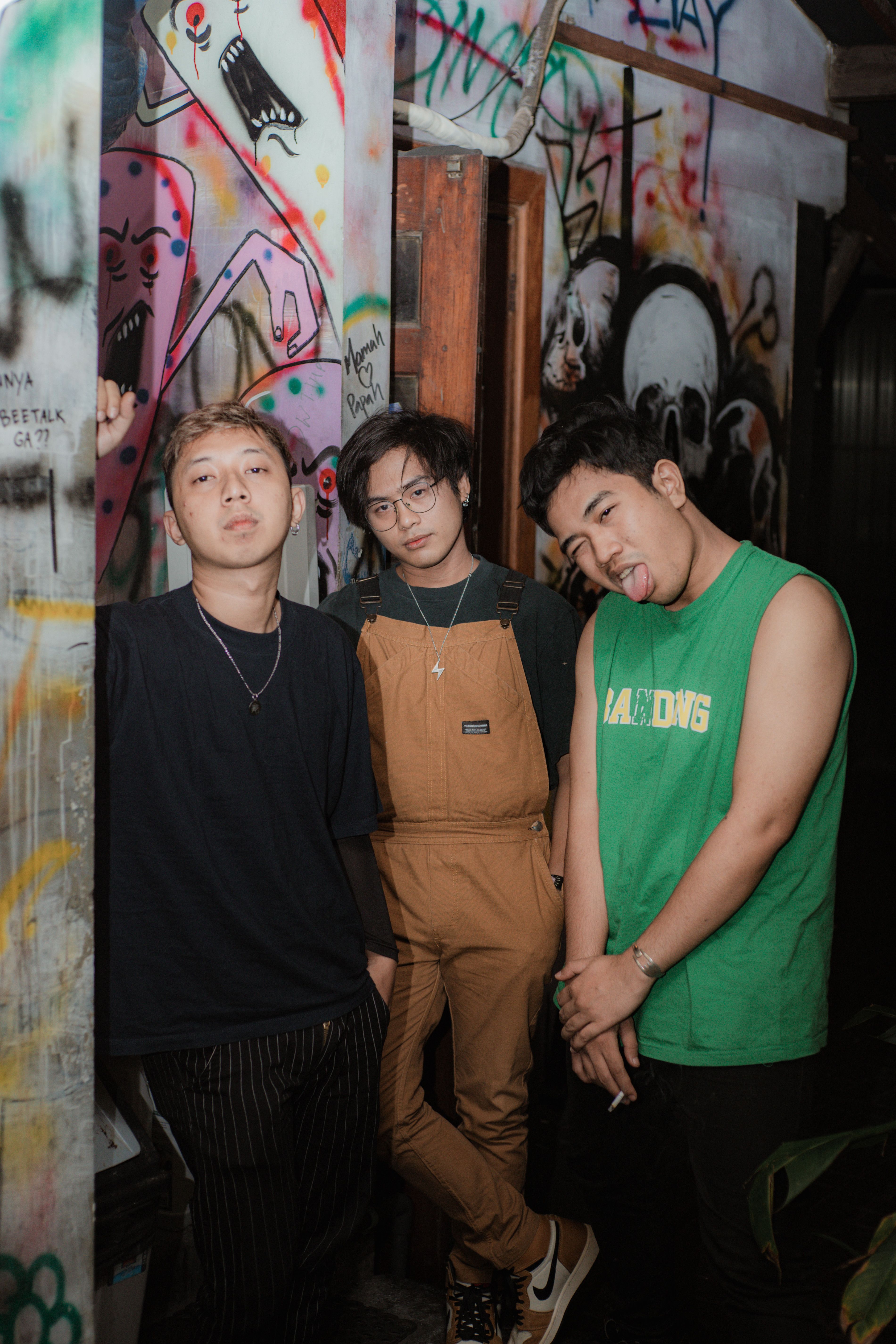 Group of young adults in an urban setting with graffiti, showcasing modern street fashion.