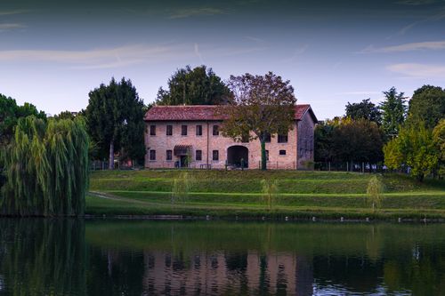 Free A tranquil rural house reflected in a lake at dusk with lush greenery surrounding. Stock Photo