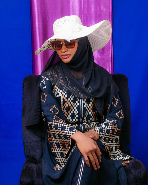 Free Fashionable woman wearing large hat and sunglasses with ethnic attire against vibrant background. Stock Photo