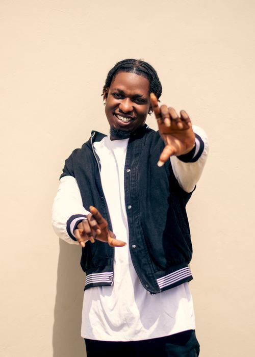 Free Cheerful young man with a braid hairstyle posing confidently against a neutral background. Stock Photo