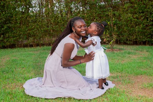 A joyful mother and daughter share a tender moment in a lush garden setting.
