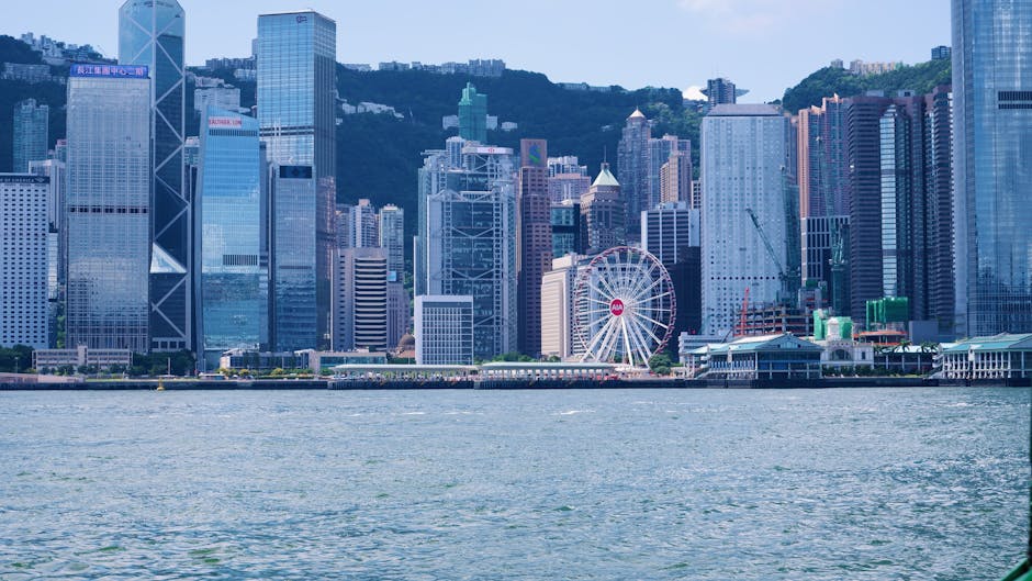 Stunning view of Hong Kong skyline with skyscrapers and observation wheel from Victoria Harbour.
