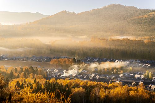 Free Beautiful autumn village scene with mist and mountains in the background. Stock Photo