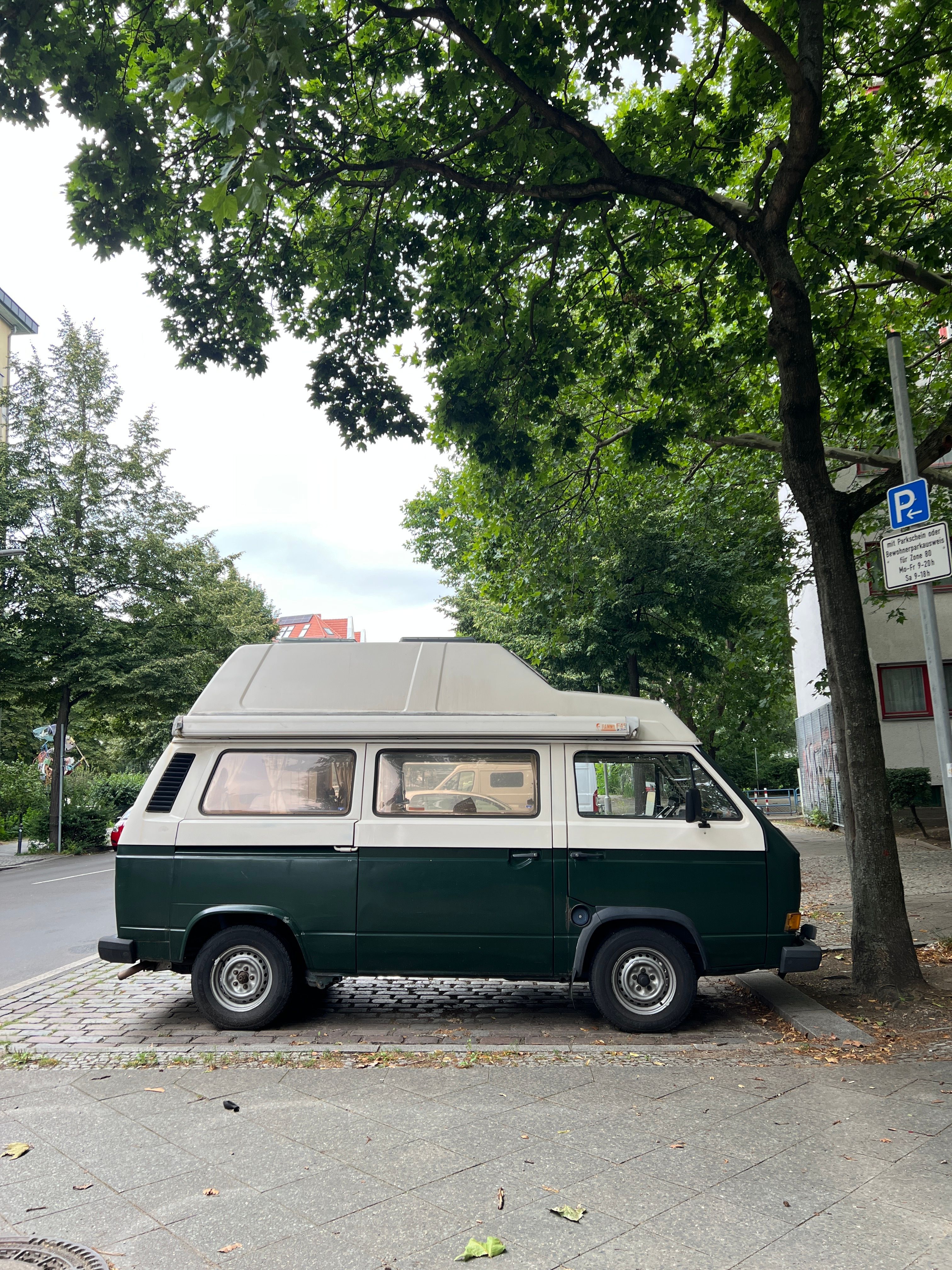 Vintage Camper Van Parked Under Green Trees · Free Stock Photo