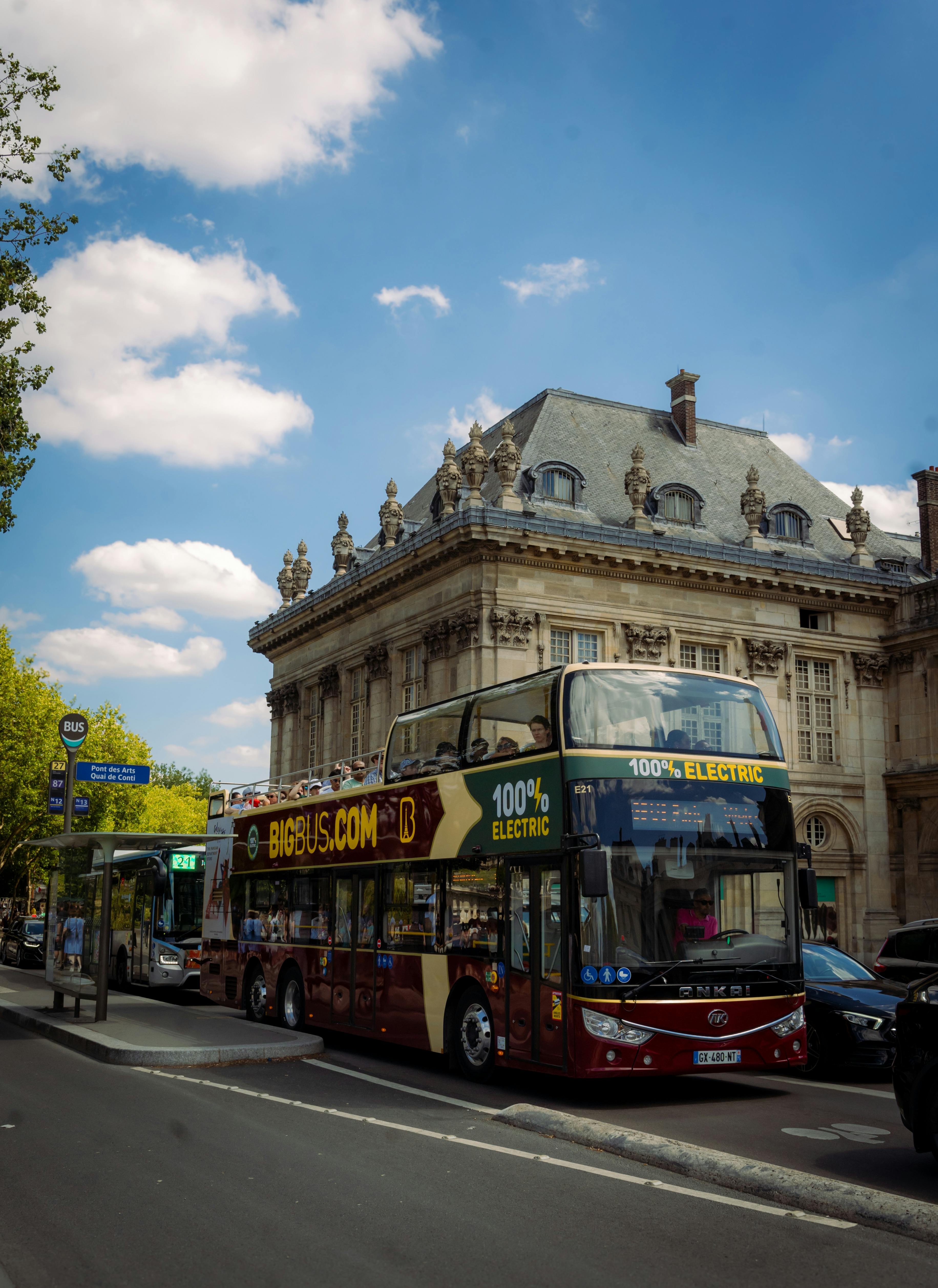 Double-decker electric bus in front of historic Parisian architecture.