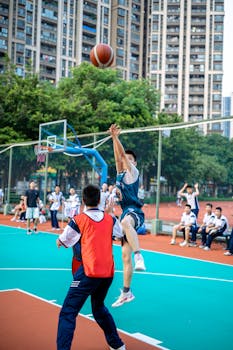 Action shot of teenagers in a basketball game on an outdoor court.