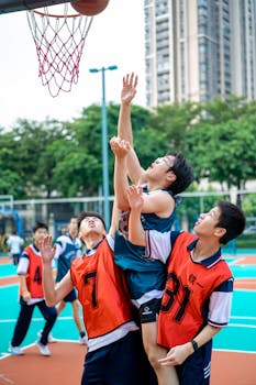 Energetic teenagers engaged in a competitive basketball game on an outdoor court.