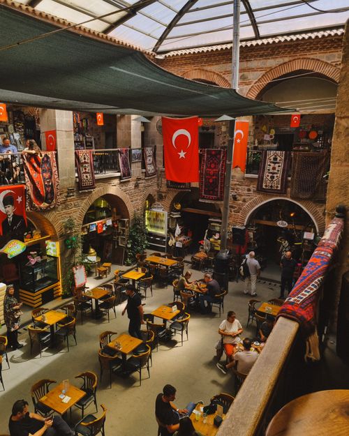 Free Busy indoor Turkish market with flags, carpets, and people dining. Stock Photo