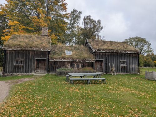 Free A historic wooden cabin with a grass roof surrounded by autumn foliage. Stock Photo