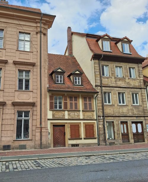 Free Facade of charming traditional European townhouses with red roofs and detailed architecture. Stock Photo