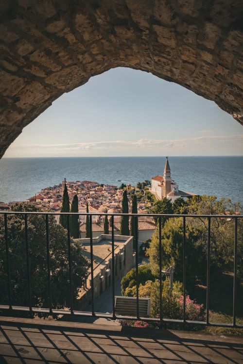 Free A stunning view of a historic European seaside town framed by a stone archway. Stock Photo