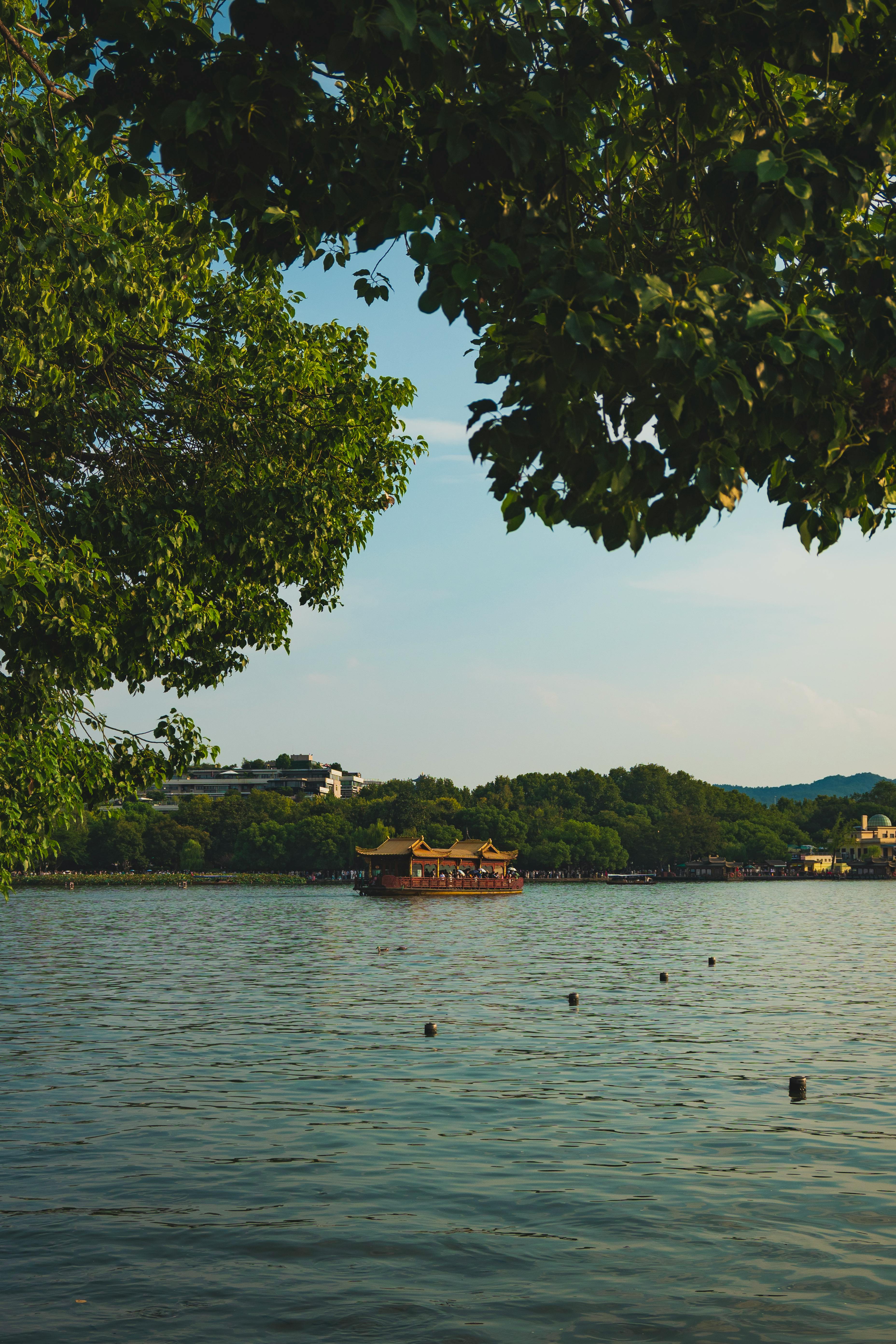 A peaceful scene of West Lake featuring a traditional boat surrounded by lush greenery.