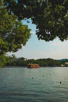 A peaceful scene of West Lake featuring a traditional boat surrounded by lush greenery.