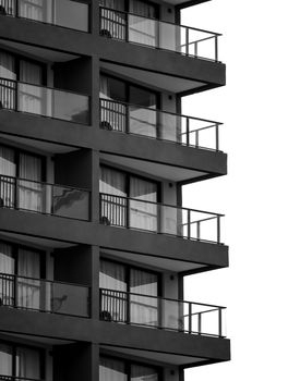 Black and white image of a modern building facade with glass balconies and geometric patterns.