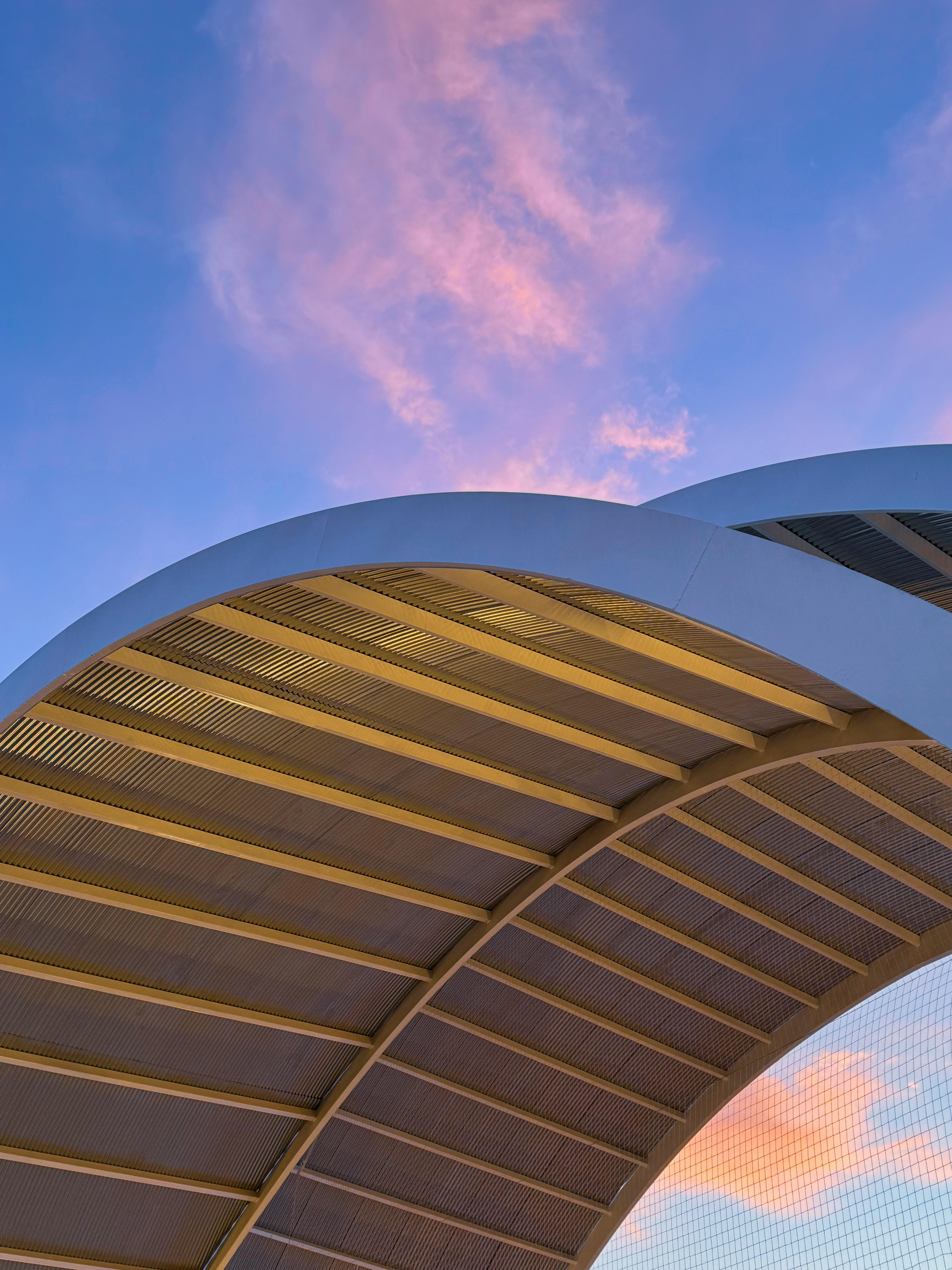 在西班牙的圣地亚哥德拉里韦拉，一座现代建筑的拱门与充满活力的日落天空形成了一幅迷人的画面