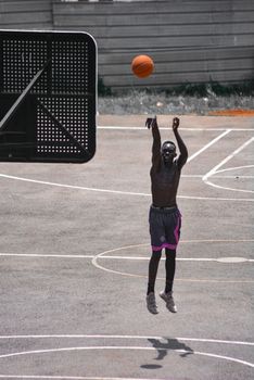 Street basketball player shoots for the hoop in Kampala, showcasing skill and determination.