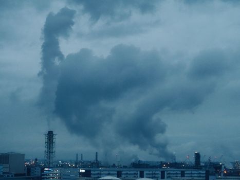 Dramatic image of smoke clouds from factories against a moody sky.