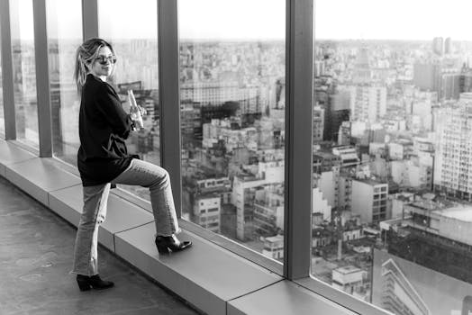 Chic woman with a drink gazes over the Buenos Aires cityscape from a modern rooftop.