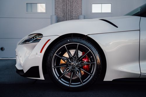 Free Close-up of a white sports car wheel with sleek alloy rims and brake calipers. Stock Photo